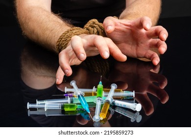 Close-up Bound Male Hands Craving For Syringes Filled With Drugs. Drug Addiction Dependence And Hostage Concept.