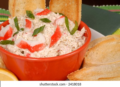 A Closeup of a bowl of crab dip with toasted crostini and lemon