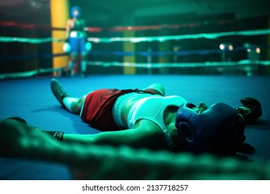 Close-up of boxer girl in knockout on ring. Two young girls boxing in gym when one girl fell down after took several blows of partner and lying on floor. Active lifestyle, hobby, womens boxing concept - Powered by Shutterstock