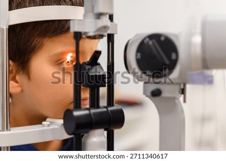 Close-up of boy undergoing eye test with slit lamp light directed at eyeball during checkup at ophthalmology clinic