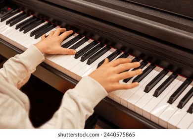 Close-up of a boy's hands on the keys of a piano, child learning to play piano - Powered by Shutterstock