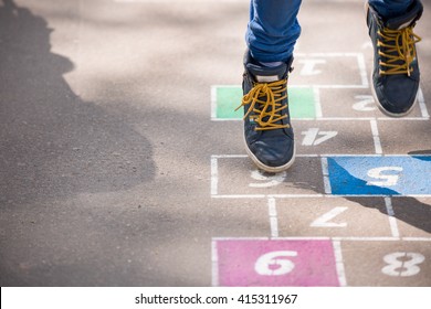 Closeup of boy's legs and hopscotch drawn on asphalt. Child playing hopscotch on playground outdoors on a sunny day. outdoor activities for children.  - Powered by Shutterstock