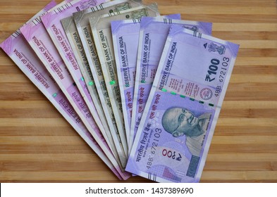 Closeup Of Brand New Colorful Indian Currency Bank Notes Of Purple 100, Green 500 And Pink 2000 Rupees Bundle Issued And In Circulation After Demonetisation Against Wooden Background