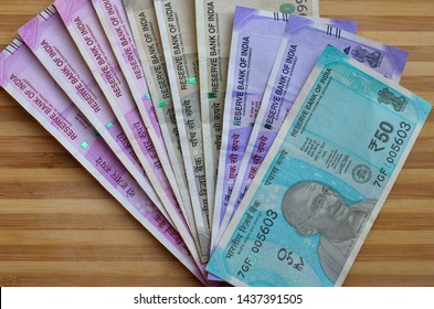 Closeup Of Brand New Colorful Indian Currency Bank Notes Of Blue 50, Purple 100, Green 500 & Pink 2000 Rupees Bundle Issued And In Circulation After Demonetisation Against Wooden Background