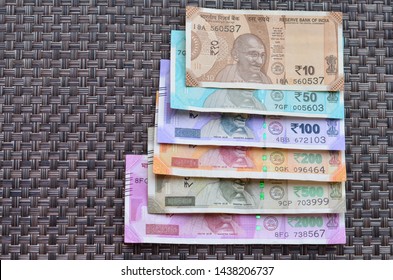 Closeup Of Brand New Colorful Indian Currency Bank Notes Of 10, 50, Purple 100, 200, 500 And Pink 2000 Rupees Bundle Issued And In Circulation After Demonetisation Against Brown Background