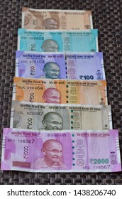 Closeup Of Brand New Colorful Indian Currency Bank Notes Of 10, 50, Purple 100, Orange 200, Green 500 & Pink 2000 Rupees Bundle Issued And In Circulation After Demonetisation Against Brown Background