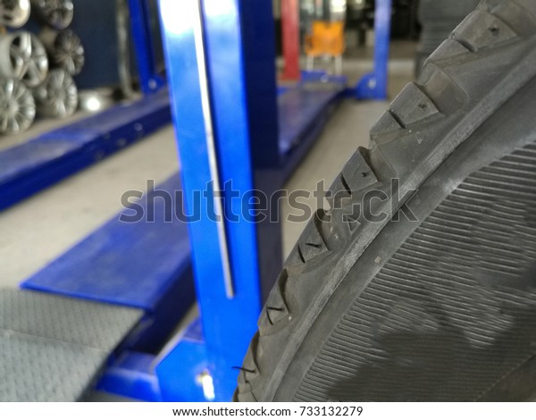 closeup of a brand new tire in\
a tire workshop with blurry background of equipment inside the\
shop
