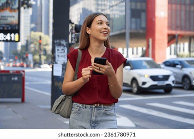 Close-up of Brazilian business woman hail a vehicle using mobile app looking to the side on Paulista Avenue, Sao Paulo, Brazil