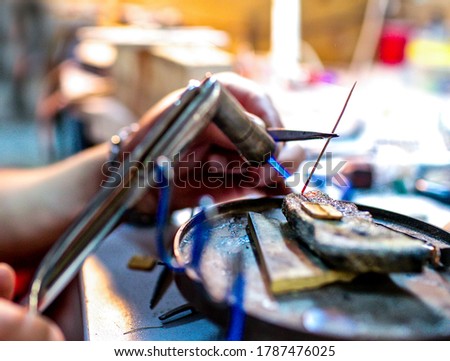 Close-up brazing process - tools in hands in jewelry workshop