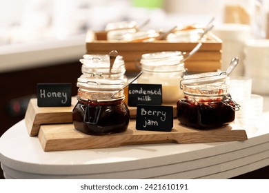 close-up breakfast buffet line serving a variety of jams in hotel with hospitality signs