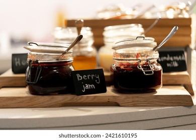 close-up breakfast buffet line serving a variety of jams in hotel with hospitality signs
