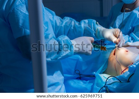 close-up breast augmentation surgery in the operating room surgeon tools implant
