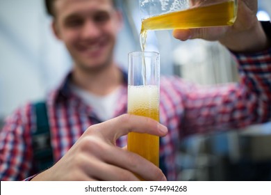 Close-up of brewer pouring beer in hydrometer cylinder at brewery factory - Powered by Shutterstock