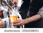 Closeup brewer pours fresh beer from steel tanker at production brewery.