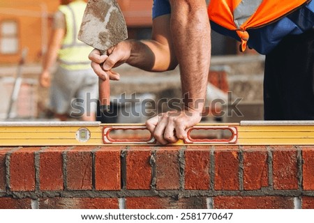 Close-up of bricklayer using a level tool to ensure brick alignment at a building site during the day