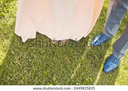 Close-up of bride's and groom's feet standing on green grass.