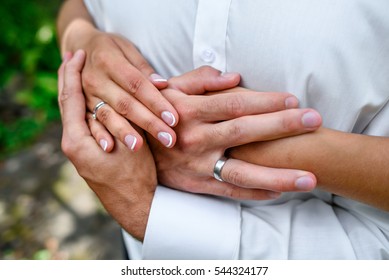 Close-up of bride's hands crossed on groom's chest