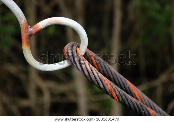 Close-up of\
Bridge steel rope connection. The black grunge cable rope that\
linking with the bridge\'s round steel\
chain.