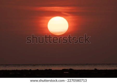 Closeup of bright big sun on the sky with yellow orange gradient colors during the sunset on the beach at Phuket, Southern of Thailand