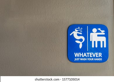 Close-up Of Bright Blue Unisex Bathroom Sign Against Neutral Colored Wall. 