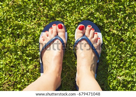 Closeup of bright flip flops and feet on green grass