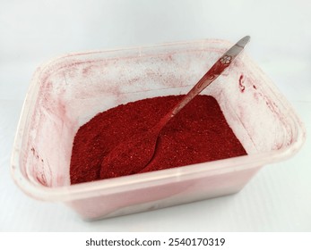 Close-up of bright red powder in a transparent container. A metallic spoon is submerged, highlighting texture and color intensity. Ideal for food, art, or industrial concepts. - Powered by Shutterstock