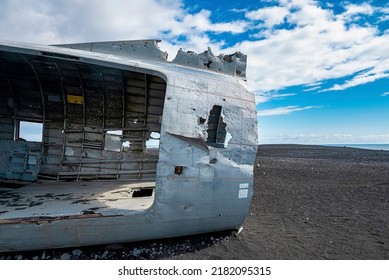 Close-up of broken airplane wreck at black sand beach. Interior of military aircraft in Solheimasandur against sky. View of tourist attraction on volcanic landscape during sunny day.