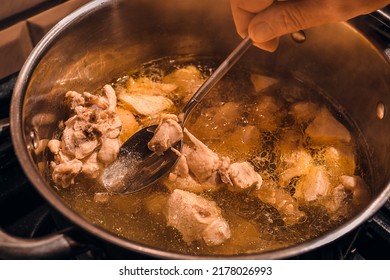 Close-up of broth and a metal spoon in a woman's hand in a steel saucepan on a stove, pieces of white chicken meat are boiled in a saucepan, top view of a hot meat broth - Shutterstock ID 2178026993