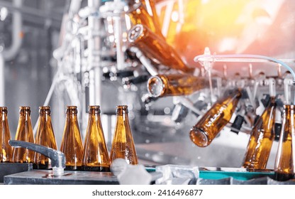 Closeup brown bottles for beer on modern, automated bottling production line in brewery. Process pasteurization, Germ removal and glass cleaning. - Powered by Shutterstock