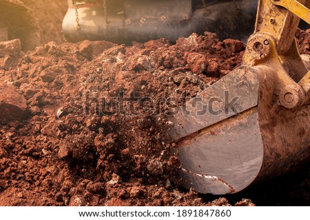 Closeup bucket of backhoe digging the soil at construction site. Crawler excavator digging on demolition site. Excavating machine. Earth moving equipment. Excavation vehicle. Construction business.