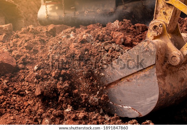 Closeup bucket of backhoe digging the soil at\
construction site. Crawler excavator digging on demolition site.\
Excavating machine. Earth moving equipment. Excavation vehicle.\
Construction business.