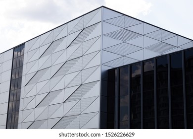 Close-up of building with triangular pattern and round openings on wall and fragment made of black glass