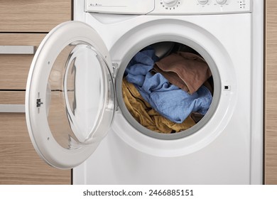 Close-up of a built-in washing machine in a home kitchen. Preparing to wash dirty clothes.