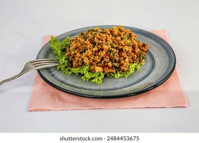 A close-up of a bulgur salad with lettuce on a blue plate, a fork beside it. - Powered by Shutterstock