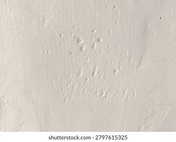 Close-up of bumpy white paint texture with air bubbles and imperfections on a wall surface.