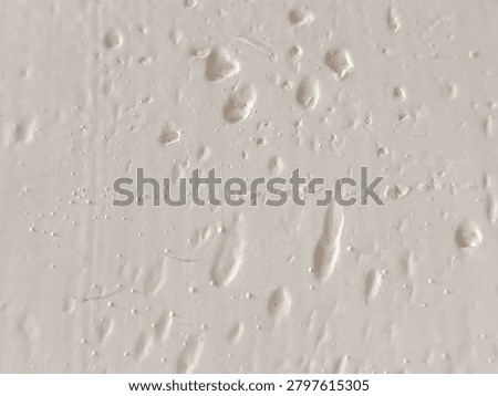 Close-up of bumpy white paint texture with air bubbles and imperfections on a wall surface.