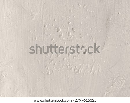 Close-up of bumpy white paint texture with air bubbles and imperfections on a wall surface.