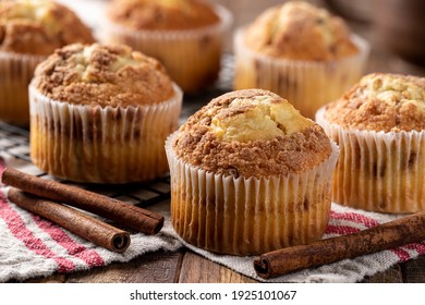 Closeup of a bunch of cinnamon muffins and cinnamon sticks on a wooden table - Powered by Shutterstock