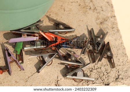 Closeup of Bunch of colorful and silver colored metal cloth clip or clipper laying on the ground in sunlight 