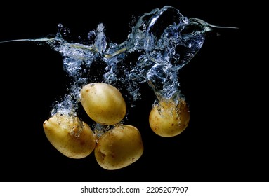 Close-up Of A Bunch Of Fresh Potatoes Splashing In A Transparent Water Tank On Black.