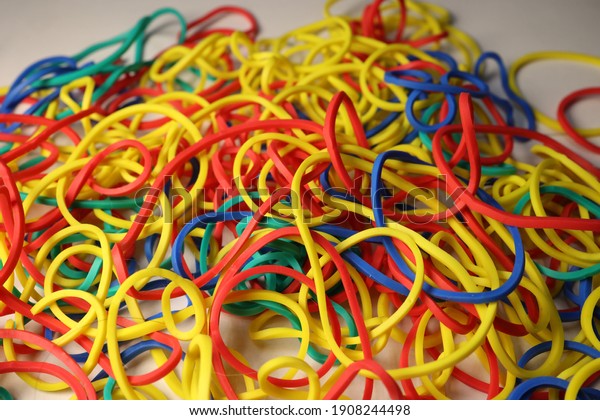 A closeup of a bunch of multicolored elastic\
rubber bands scattered on the\
table