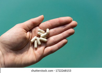 Close-up of bunch of pills in female hand on green background. Concept of first aid, medical care during illness. - Shutterstock ID 1722268153