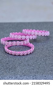 A Closeup Of A Bunch Of Pink Silver Bangles Over A Gray Background