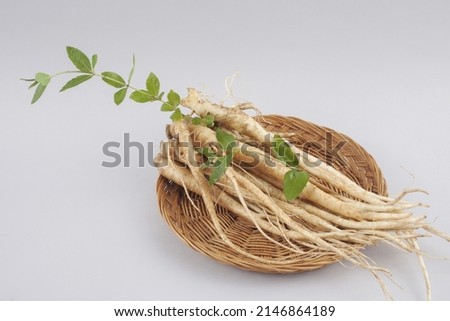 Close-up of a bundle of bellflower roots with green leaves on a bamboo basket, South Korea
