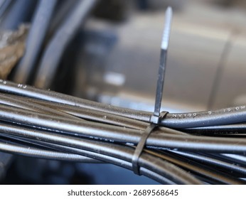 Close-up of a bundle of black electrical cables or wires neatly secured together with a black plastic zip tie in a technical or industrial setting.