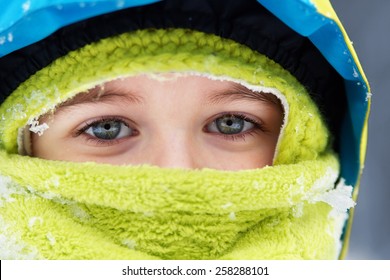 Closeup of bundled up blue eyed little boy with snow flakes details            