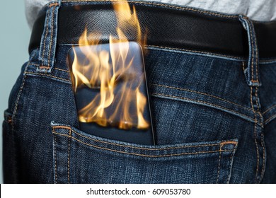 Close-up Of A Burning Phone Inside The Back Pocket Of Jeans