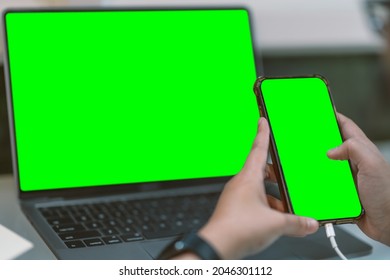 Close-up of business female wearing smartwatch working with and hand holding of smartphone with empty green screen and laptop in coffee shop like the background. - Powered by Shutterstock