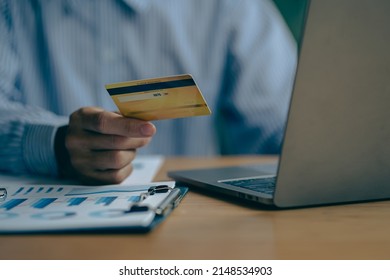 Close-up Of Business Holding Credit Card To Check Account Balance Use An Online Banking App On Your Laptop. Online Payment Typewriter Hand Shopping Keyboard On The Notebook