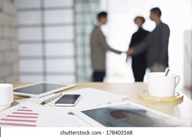 close-up of business items with people meeting in background.